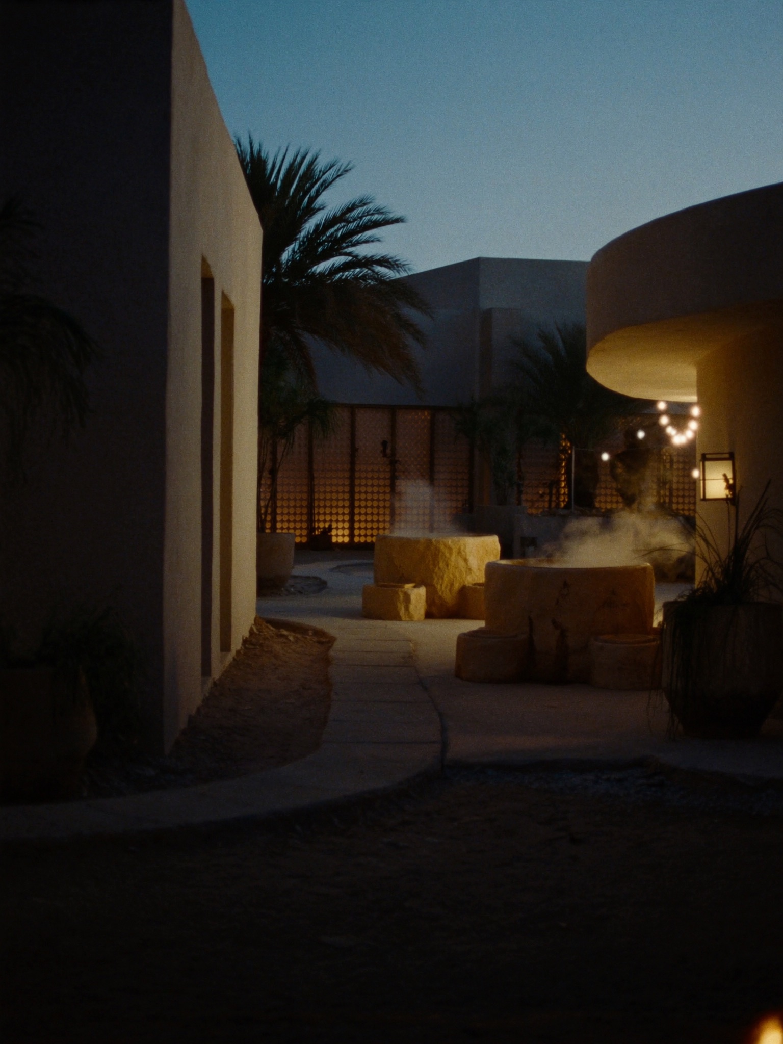 Desert Hot Springs Spa Hotel courtyard at dusk with steaming hot tubs.