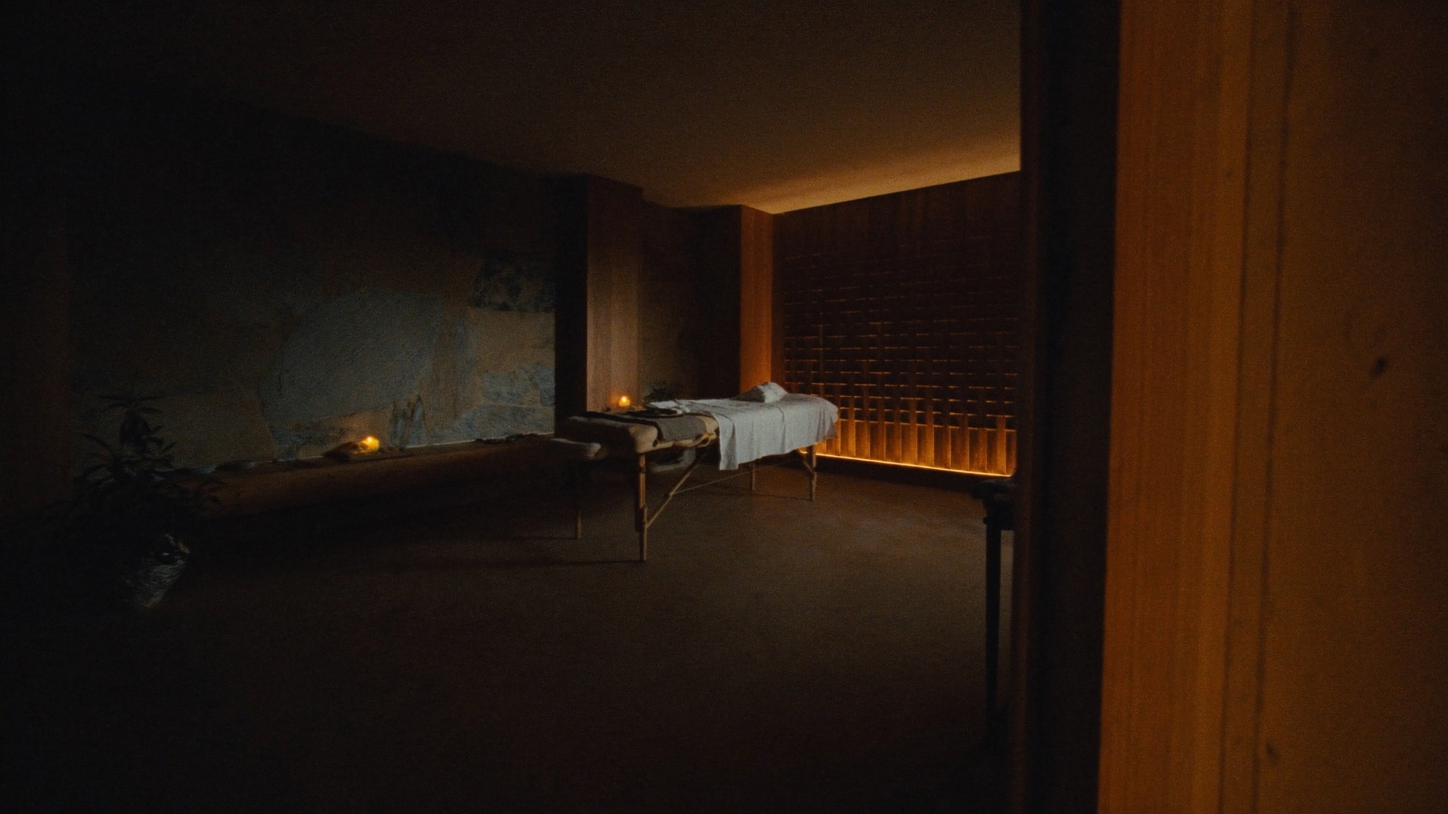 Quiet desert spa treatment room in warm candlelight with natural stone walls.